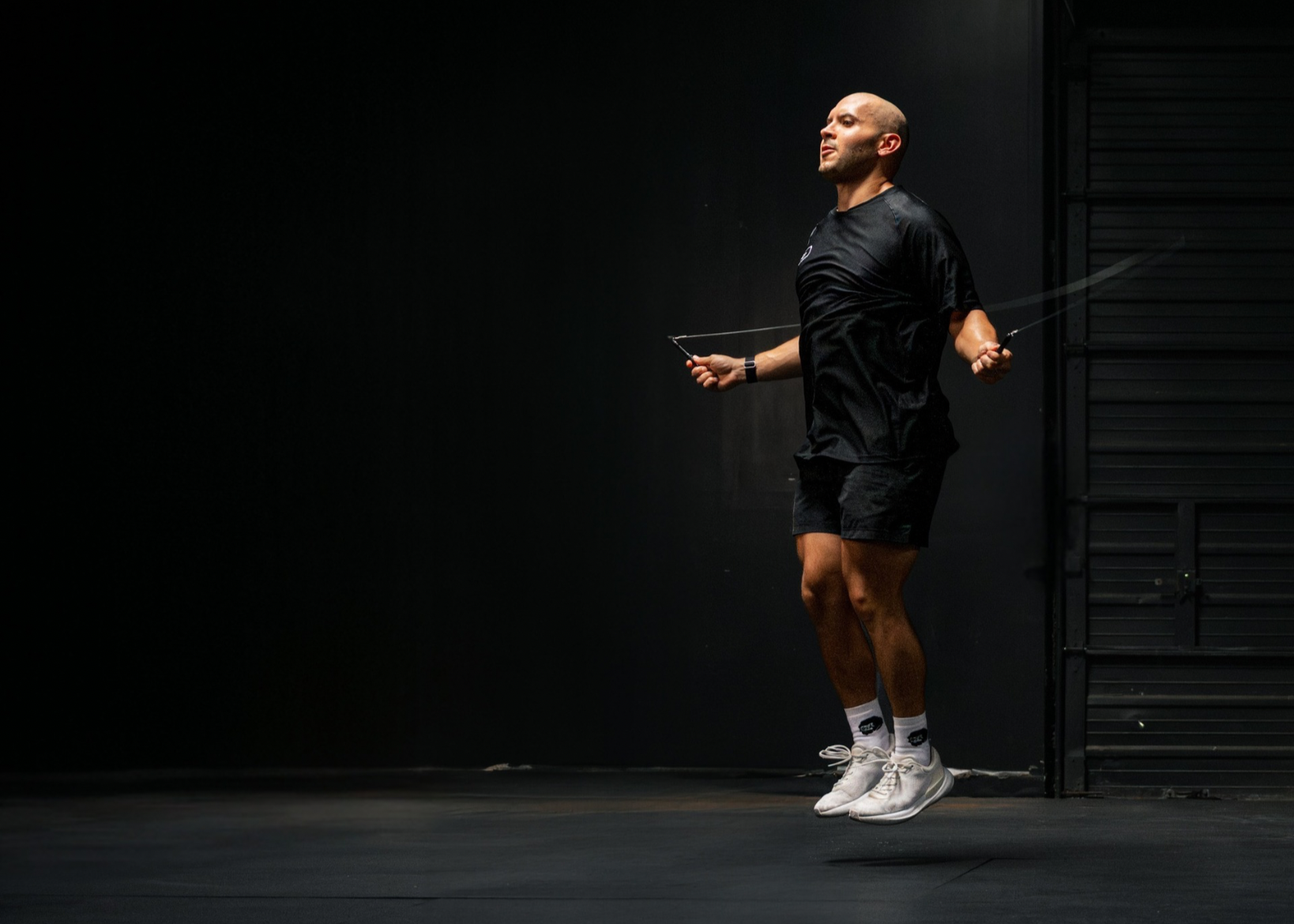 Person jumping rope in a dark indoor setting