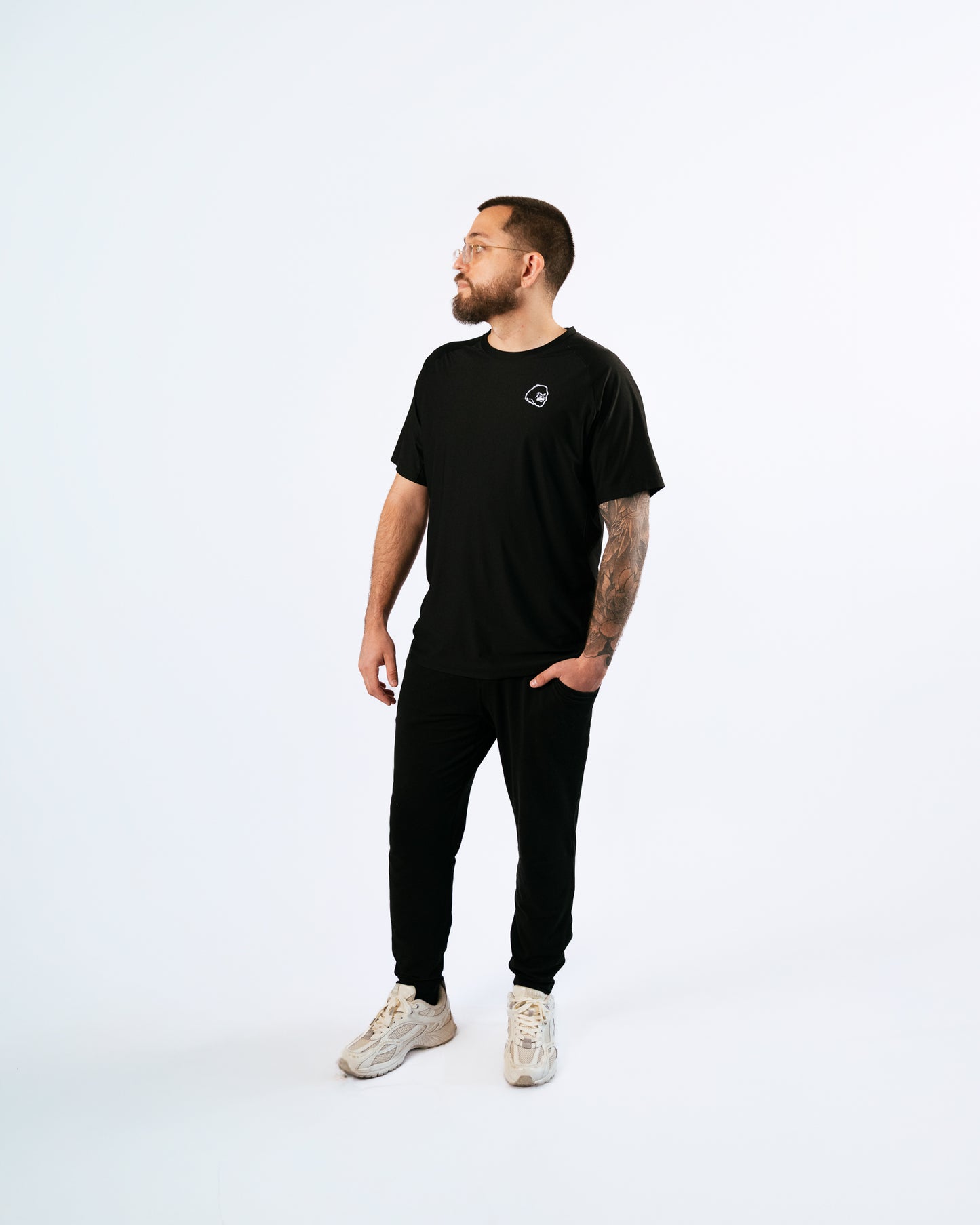 Man wearing a black t-shirt with a gorilla logo and pants on a white background