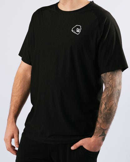 Person wearing a black t-shirt with a gorilla logo on a light gray background